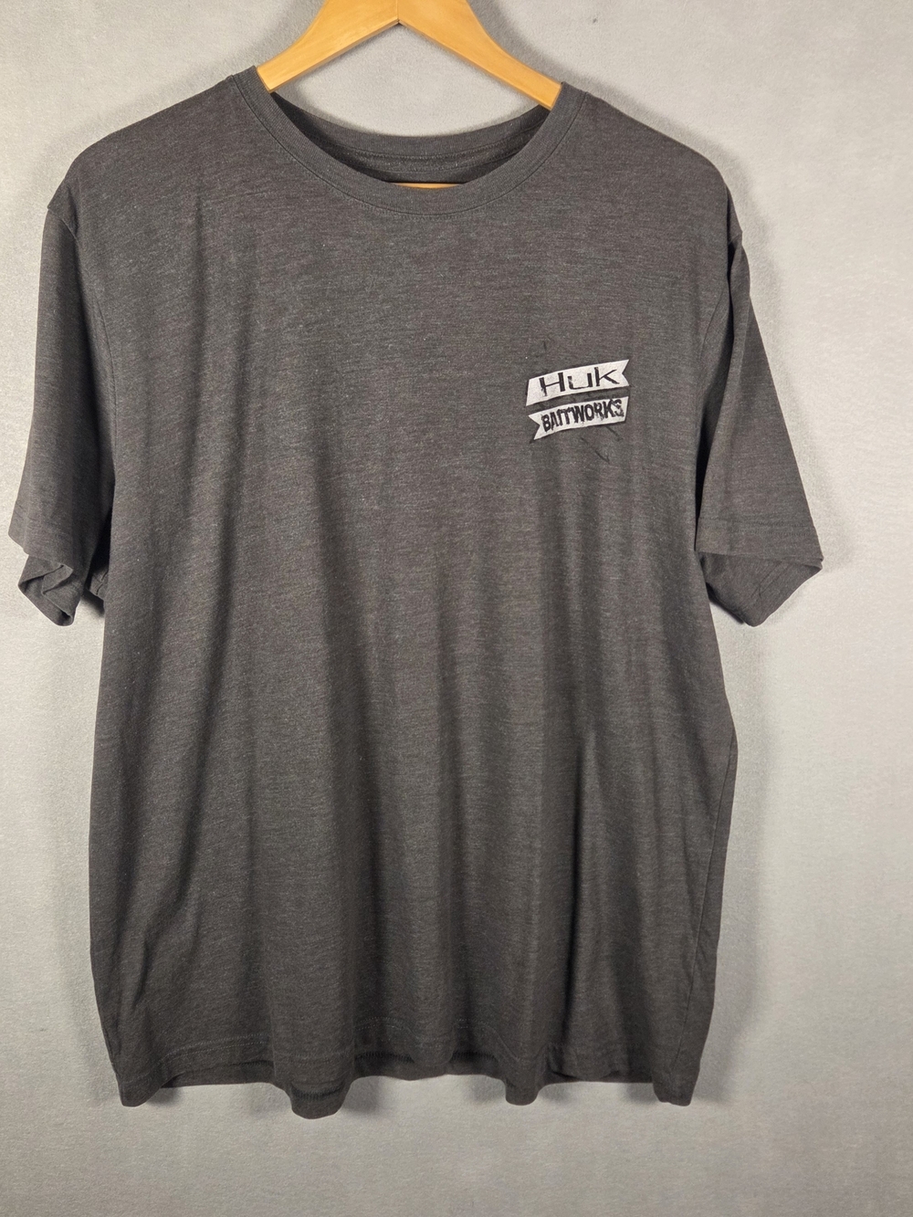 Huk Baitworks T-shirt features a graphic of a hand holding a fish (T620)